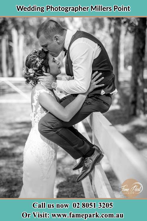 Groom kiss the Bride while sitting on the fence Millers Point NSW 2000